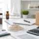 Earthworm peptide powder cost planning with sample vials, documents, calculator, and shipping carton in a laboratory workspace