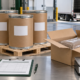 Conceptual export inspection station with closed fiber drums, pallet, sealed inner pouch in a carton, barcode scanner, packing clipboard, and digital scale
