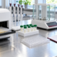 Conceptual enzyme assay workstation with plate reader, microplates, pipettes, sample vials, analytical balance, insulated carrier, and laboratory record sheet