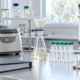 Conceptual biochemical separation bench with closed centrifuge, filtration glassware, capped collection tubes, chromatography column, and process binder
