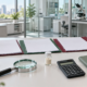 Conceptual ingredient market research desk with separate folders, sample vial, magnifying glass, calculator, notebook, and capped sample tubes