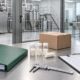Conceptual manufacturer consultation table with process folder, sample vials, packing carton, caliper, clipboard, and telephone beside a generic processing room